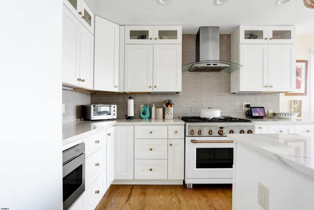 a kitchen with stainless steel appliances granite countertop a stove a sink and white cabinets