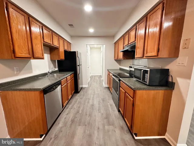 a kitchen with granite countertop a stove top oven a sink a window and cabinets