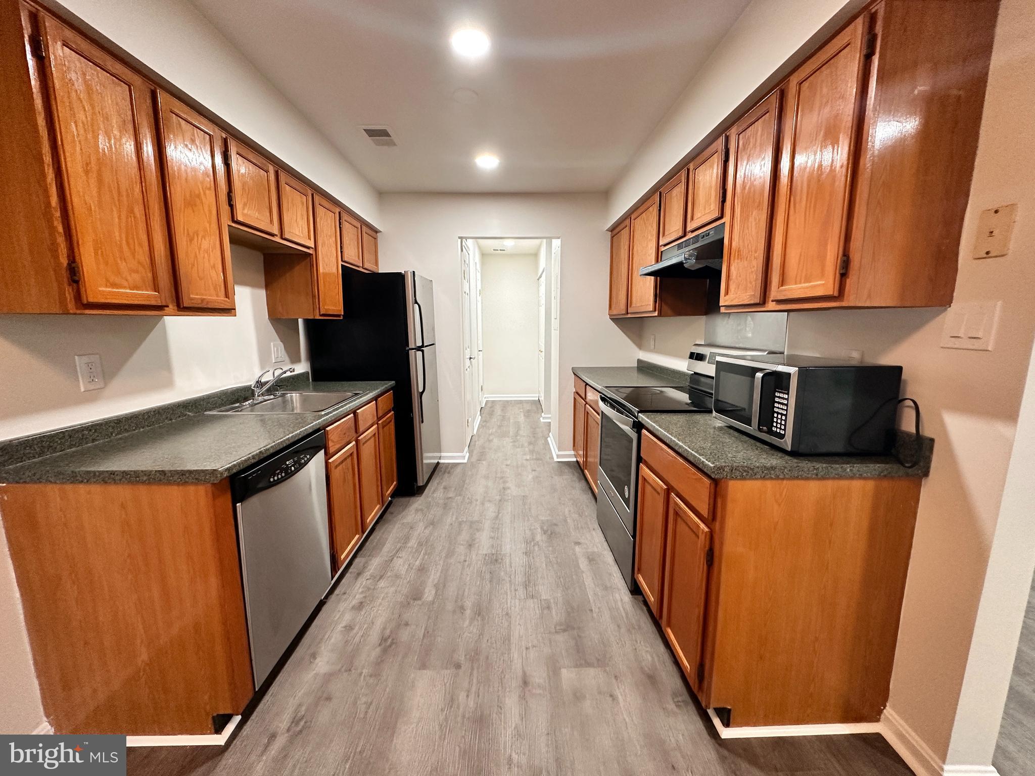 31 Amarillo Court, Unit 113 Germantown, MD 20874 - Photo 8 of 24 a kitchen with stainless steel appliances granite countertop wooden cabinets a refrigerator and a sink