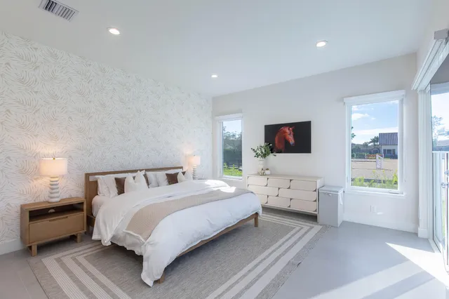 a bedroom with a bed and large windows