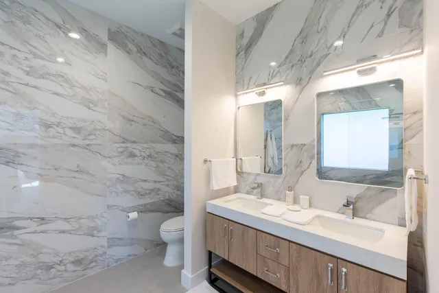 a bathroom with a granite countertop sink a toilet and a mirror