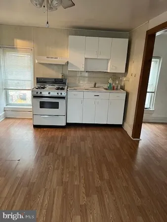 a kitchen with stainless steel appliances wooden floors and a view of living room