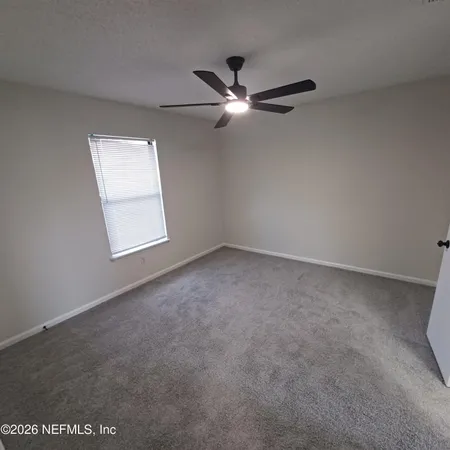 an empty room with windows and fan