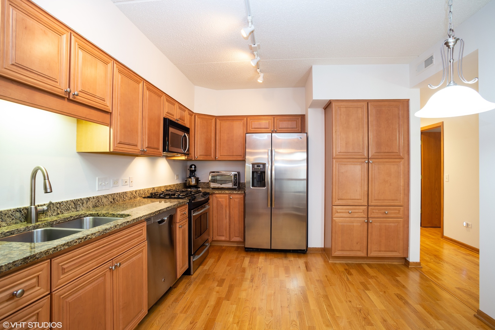 601 West Rand Road, Unit 202A Arlington Heights, IL 60004 - Photo 5 of 10 a kitchen with stainless steel appliances granite countertop a refrigerator a sink dishwasher and a stove with wooden floor