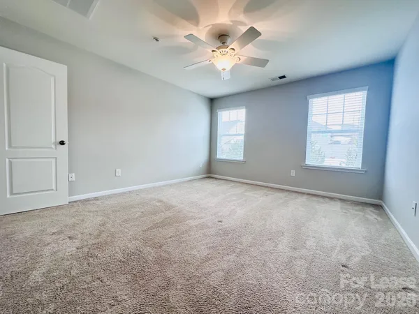 an empty room with windows and ceiling fan