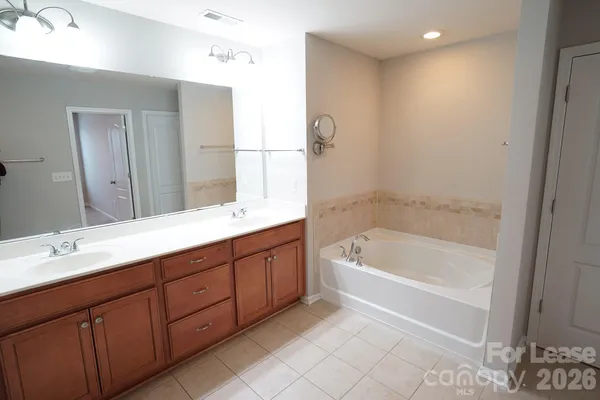 a spacious bathroom with a tub sink and mirror