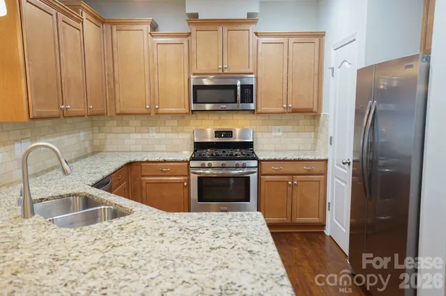a kitchen with granite countertop a refrigerator stove and sink