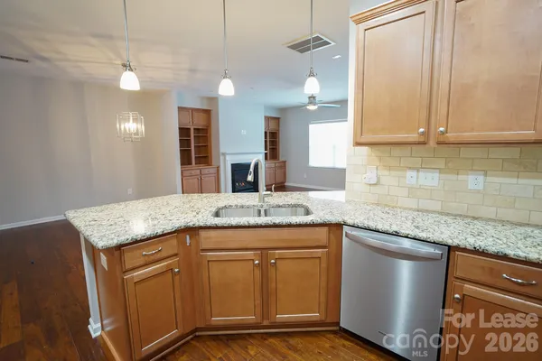 a kitchen with stainless steel appliances granite countertop a sink a stove and a wooden cabinets