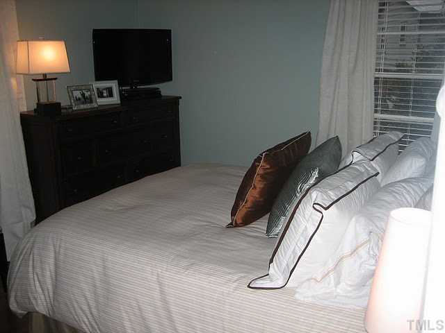 3535 Brentwood Road Raleigh, NC 27604 - Photo 7 of 12 a bed sitting in a bedroom next to a lamp