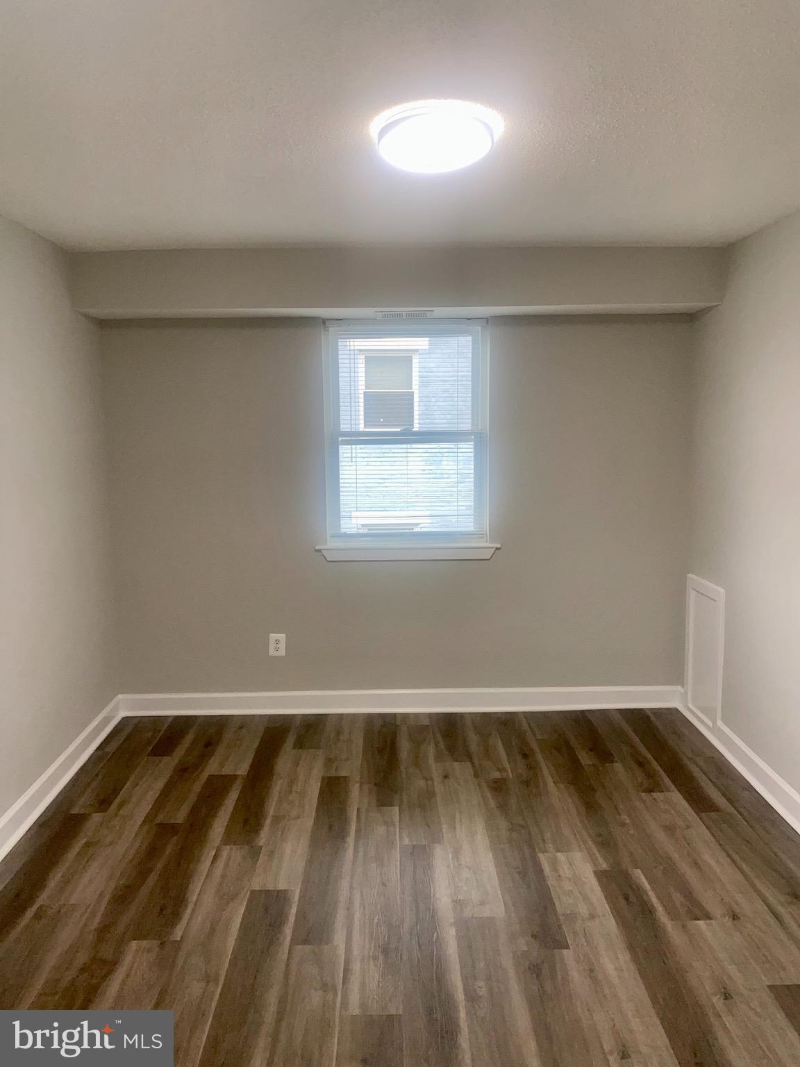 718 Brandywine Street Southeast, Unit 202 Washington, DC 20032 - Photo 3 of 10 an empty room with wooden floor and windows