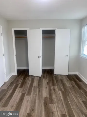 a view of an empty room with wooden floor and closet
