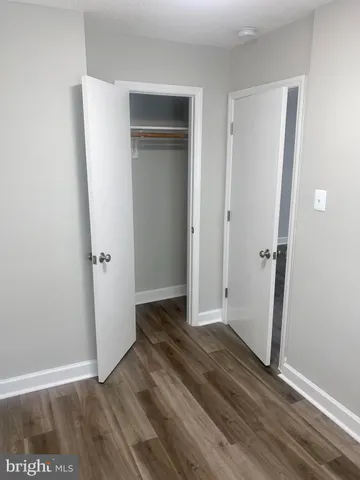 an empty room with wooden floor and a bathroom