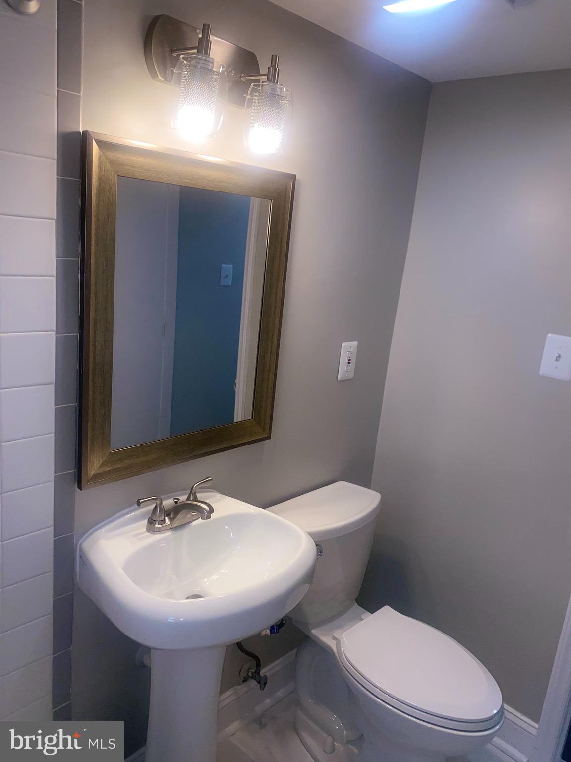 718 Brandywine Street Southeast, Unit 202 Washington, DC 20032 - Photo 10 of 10 a bathroom with a toilet sink and mirror