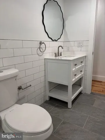 a view of an empty room with wooden floor and a kitchen