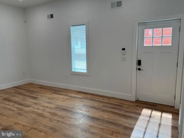 a view of a hallway with wooden floor and a bathroom