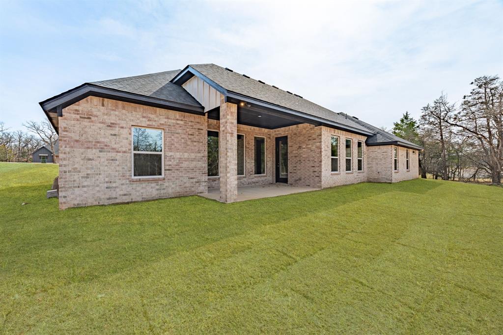 2017 Forest Bridge Azle, TX 76020 - Photo 28 of 30 Back of house featuring brick siding, a yard, a patio area, and a shingled roof