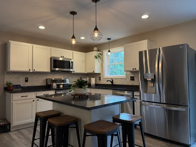 a kitchen with refrigerator a sink and chairs