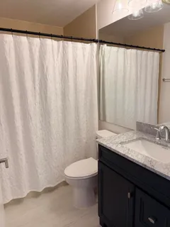 a bathroom with a granite countertop sink and a toilet