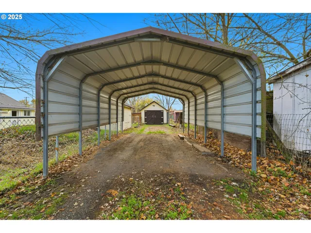 a view of a backyard with grass and a barn