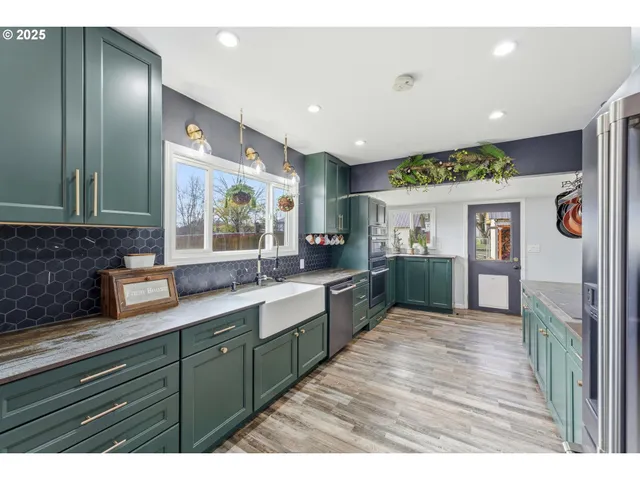 a large kitchen with stainless steel appliances granite countertop a large counter top a sink and a refrigerator