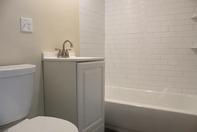a bathroom with a toilet a sink a mirror and bathtub