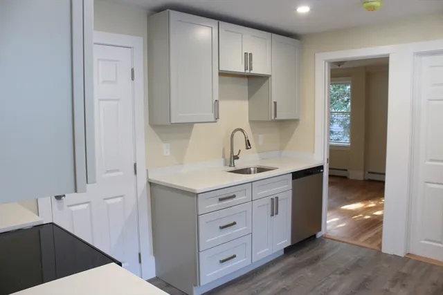 a kitchen with white cabinets and sink
