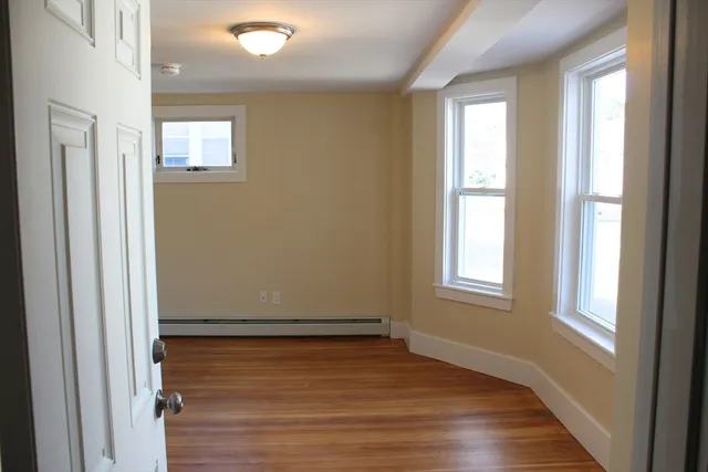 a view of an empty room with wooden floor and a window