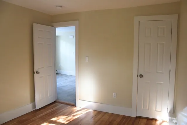 an empty room with wooden floor & closet area