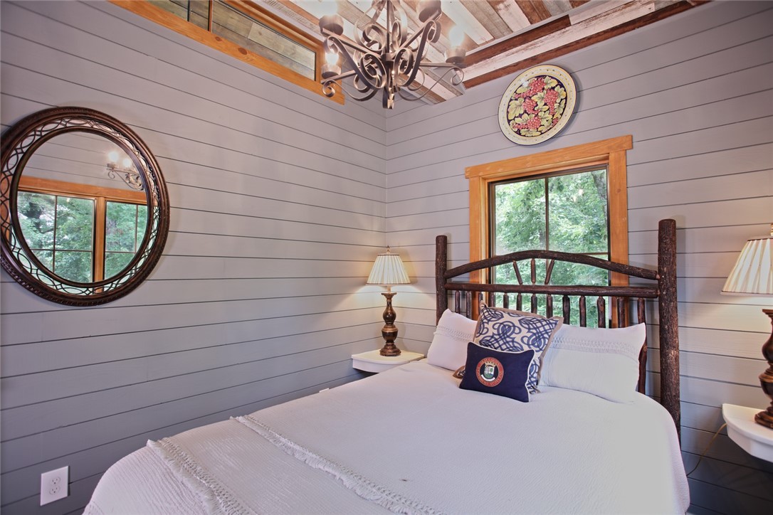 275 Jocassee Lake Road Salem, SC 29676 - Photo 12 of 41 This cozy bedroom features shiplap walls, wood-trimmed windows, and a rustic wood bed frame.
