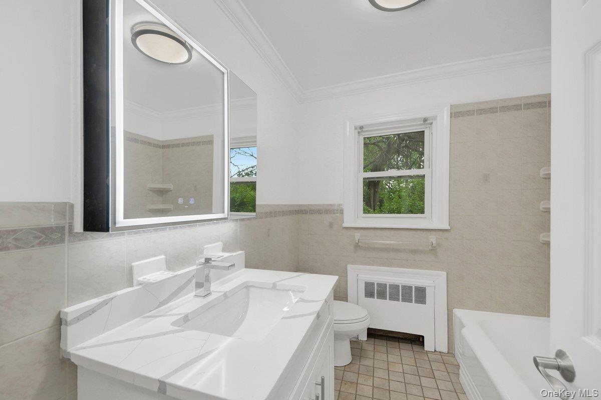 7 Rutledge Road Valhalla, NY 10595 - Photo 12 of 37 Full bathroom featuring a vanity with a white countertop and chrome faucet, an illuminated mirrored medicine cabinet, and light-toned tile flooring