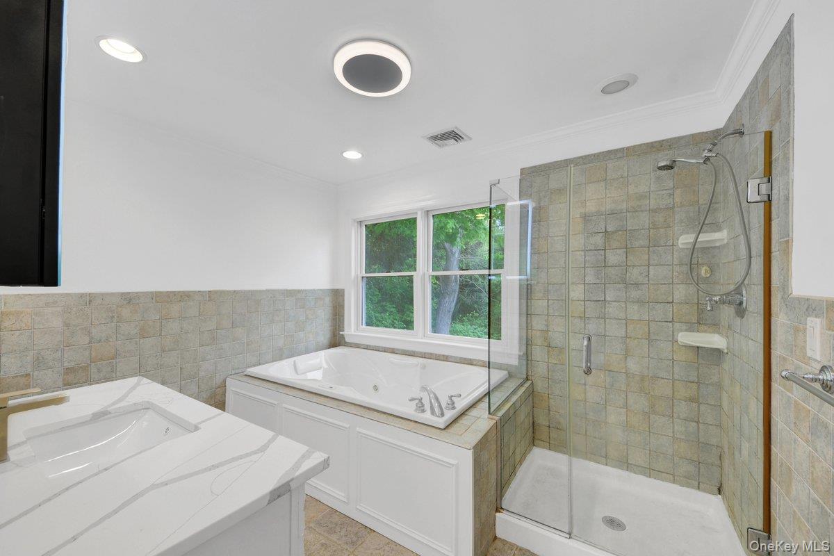 7 Rutledge Road Valhalla, NY 10595 - Photo 22 of 37 Bathroom featuring a tiled glass-enclosed shower, built-in jetted tub, and a vanity with an integrated sink and quartz-finish countertop