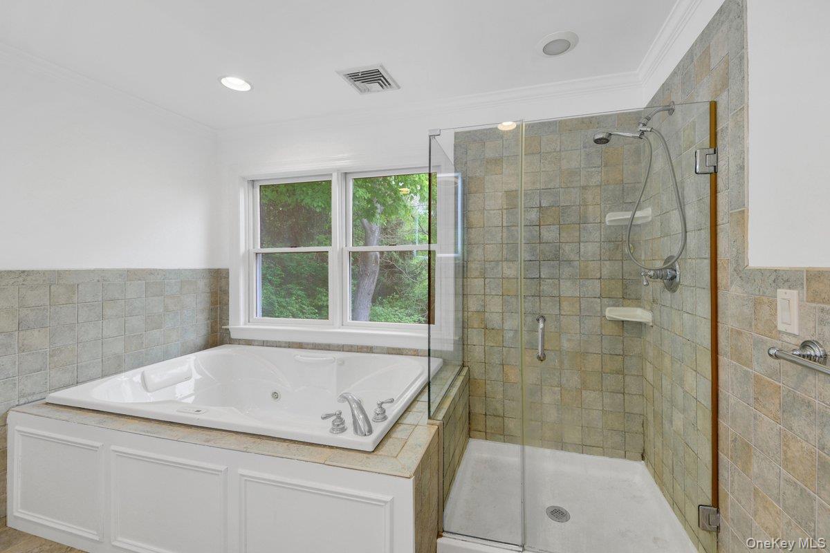 7 Rutledge Road Valhalla, NY 10595 - Photo 23 of 37 Bathroom featuring a built-in jetted tub, a separate glass-enclosed shower with a handheld showerhead, and tiled walls