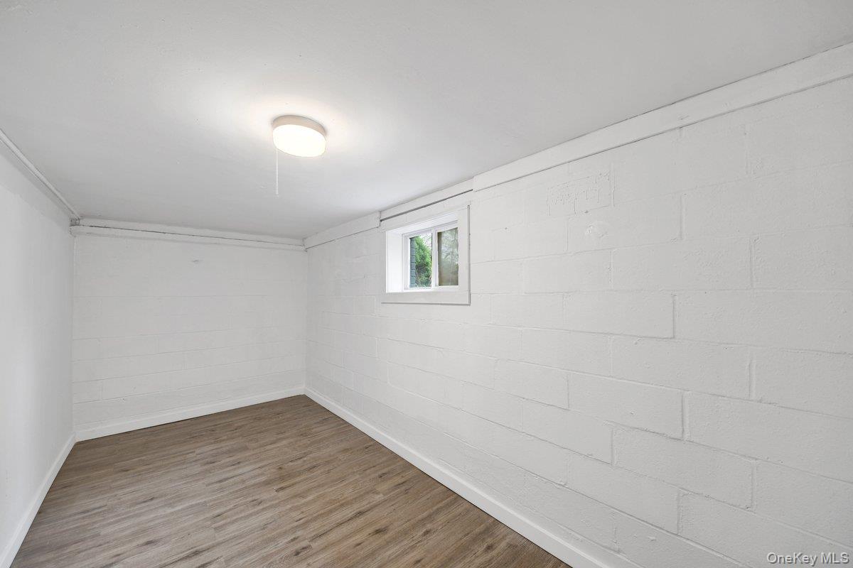 7 Rutledge Road Valhalla, NY 10595 - Photo 29 of 37 Finished interior space featuring wood-finish flooring, white painted block walls, a single window, and an overhead flush-mount light fixture