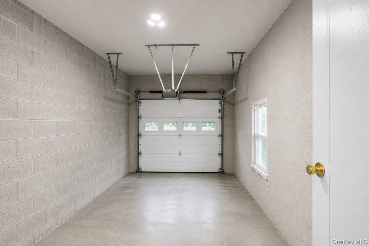 7 Rutledge Road Valhalla, NY 10595 - Photo 31 of 37 Spacious garage featuring a concrete block wall, smooth concrete flooring, and a white paneled garage door with upper window inserts
