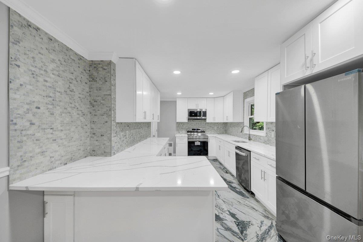 7 Rutledge Road Valhalla, NY 10595 - Photo 4 of 37 Contemporary kitchen featuring white cabinetry, stainless steel appliances, white countertops with veining, a mosaic tile backsplash, and patterned flooring