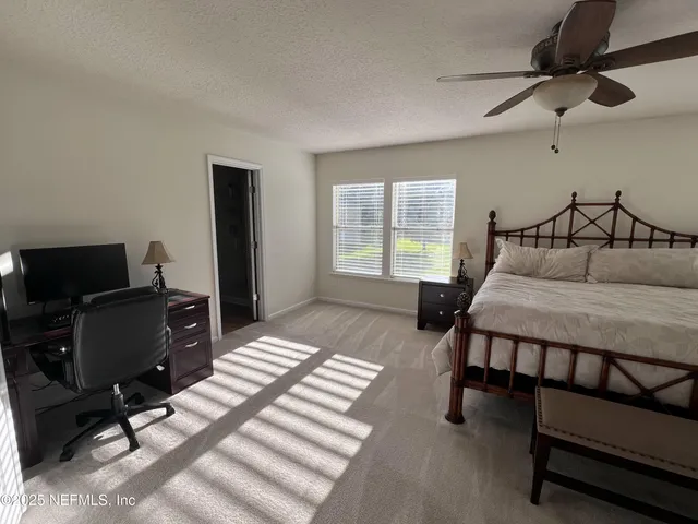 a bedroom with a bed a desk and chair with wooden floor