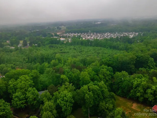 an aerial view of residential houses with outdoor space and trees