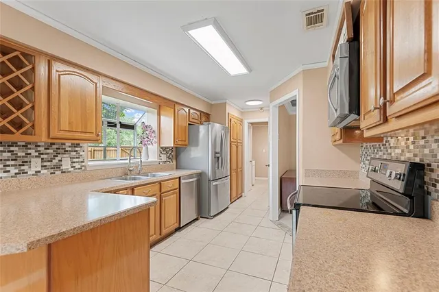 a large kitchen with a stove a sink dishwasher a refrigerator and wooden cabinets