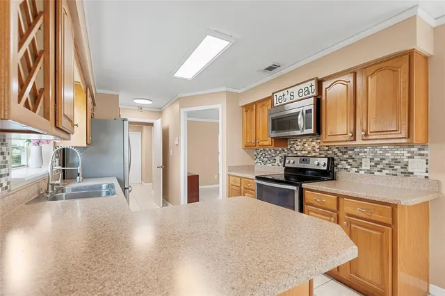 a kitchen with stainless steel appliances granite countertop a stove top oven a sink dishwasher and a refrigerator with wooden floor