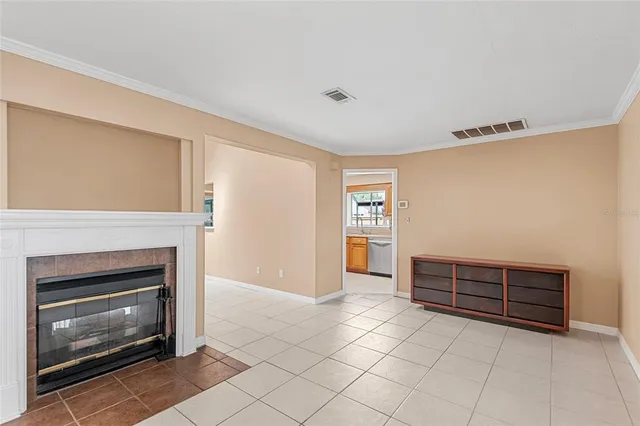 a view of kitchen and empty room with fireplace