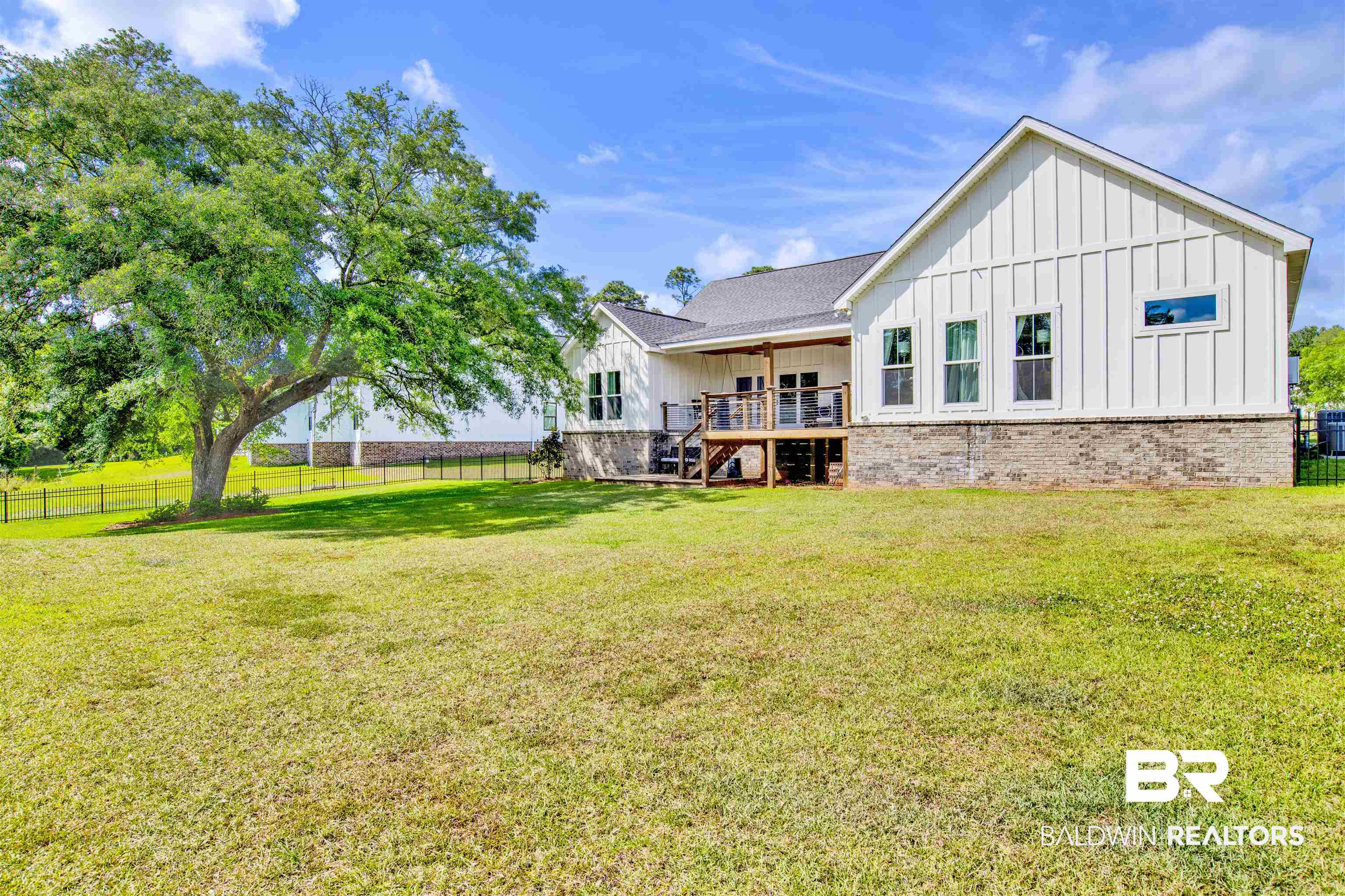 21621 Veranda Boulevard Fairhope, AL 36532 - Photo 42 of 51 Back of property featuring a deck, a fenced backyard, stairs, board and batten siding, and a lawn