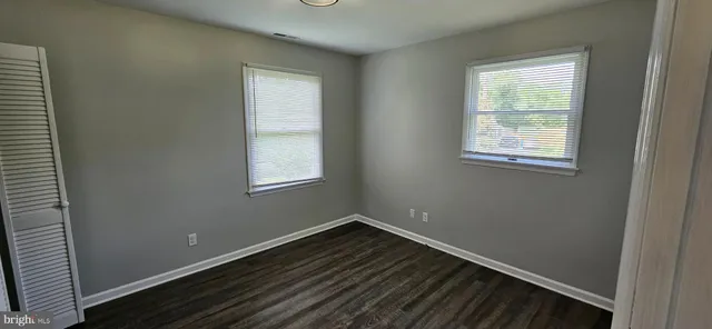 a view of an empty room with closet and wooden floor