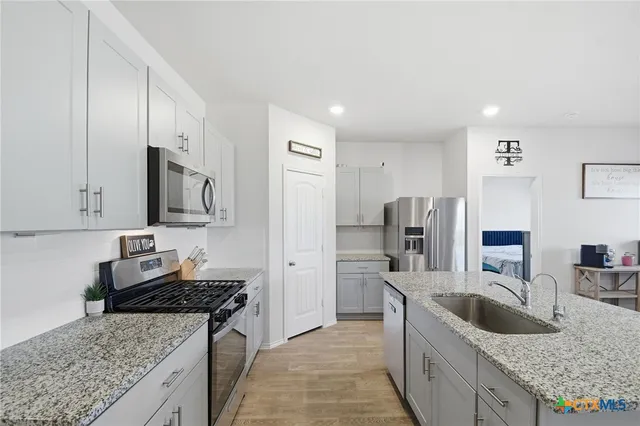 a kitchen with granite countertop a sink a counter top space stainless steel appliances and cabinets