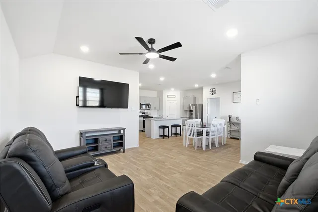 a living room with furniture a flat screen tv and kitchen view