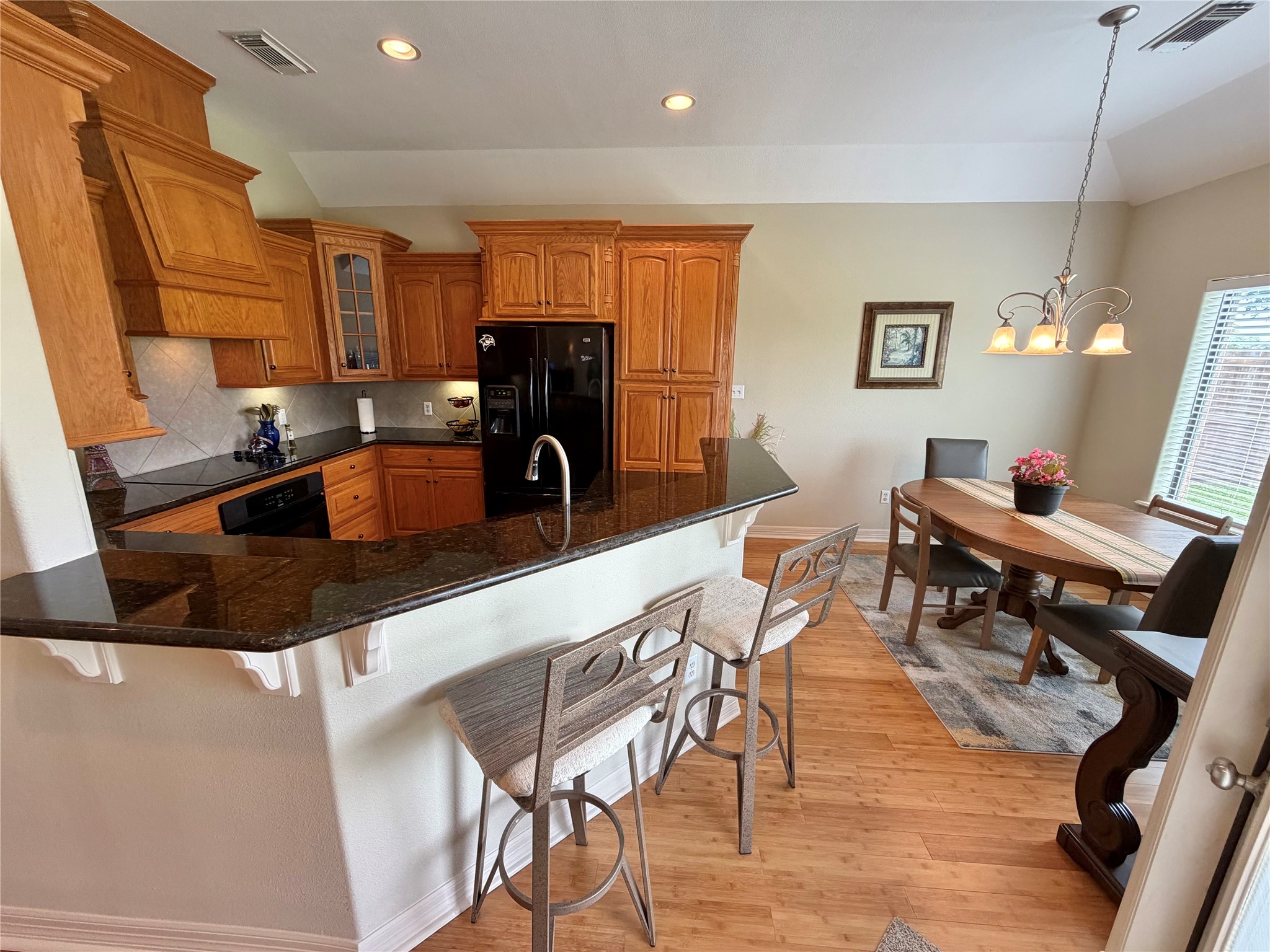 1448 South Blue Bonnet Lane Angleton, TX 77515 - Photo 10 of 43 a kitchen with stainless steel appliances granite countertop a table chairs and a refrigerator