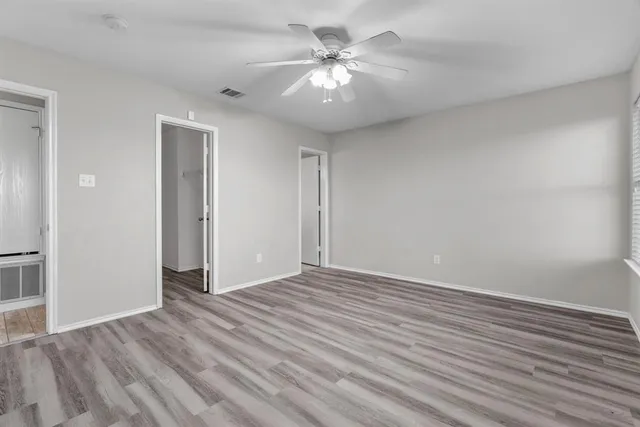 wooden floor in an empty room with a chandelier fan
