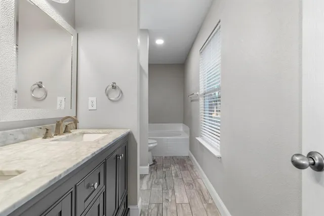 a bathroom with a granite countertop sink a toilet and a large mirror
