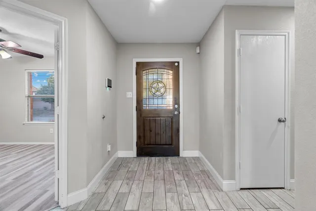 a view of an empty room with wooden floor and a window
