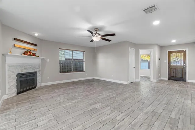 an empty room with windows and fireplace