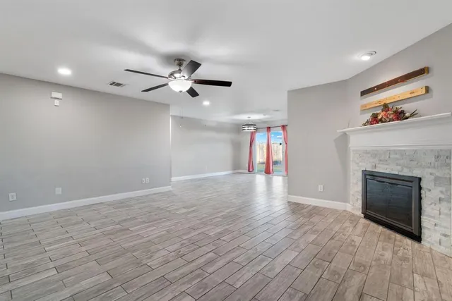 a view of an empty room with wooden floor fireplace and a window